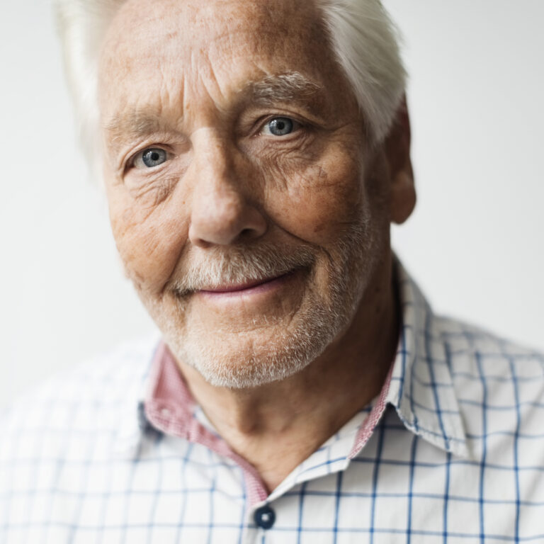 Portrait of smiling senior man against white background