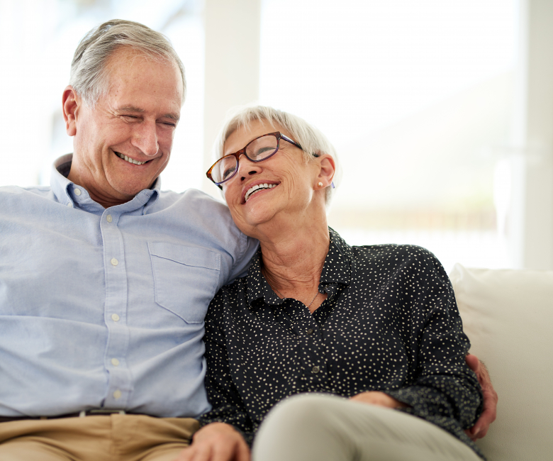 Cropped shot of an affection senior couple laughing while relaxing on their sofa at home